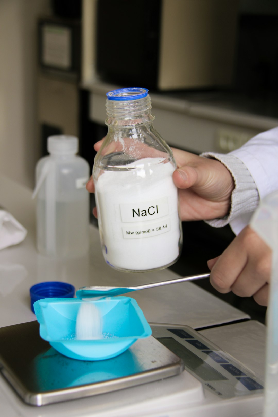A technician pouring NaCl on a scale in a science laboratory.